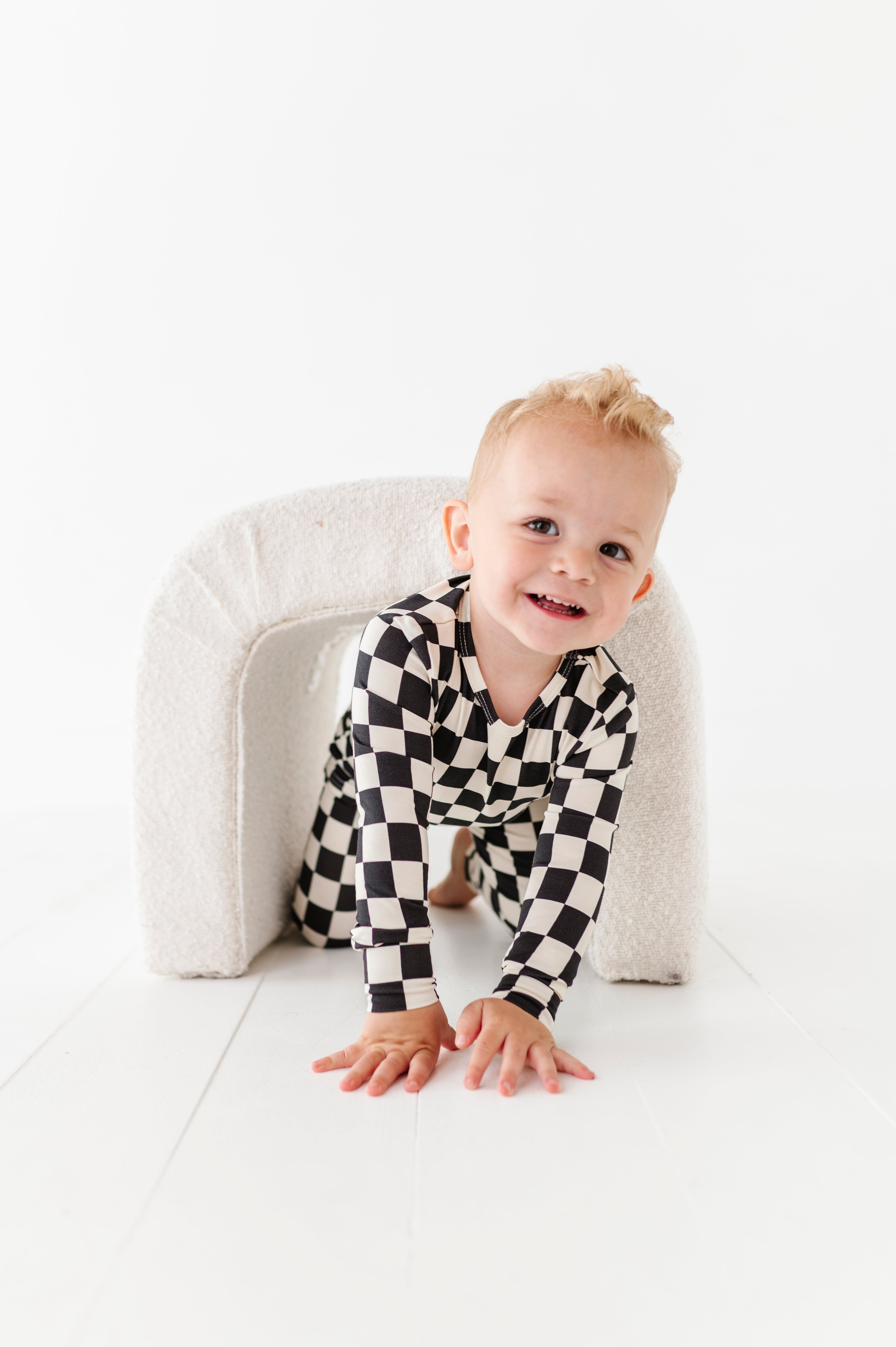 boy playing while wearing Black checkered 2-piece pajamas for toddlers and kids, featuring a comfy fit and elastic waistband by Rad Toddler.
