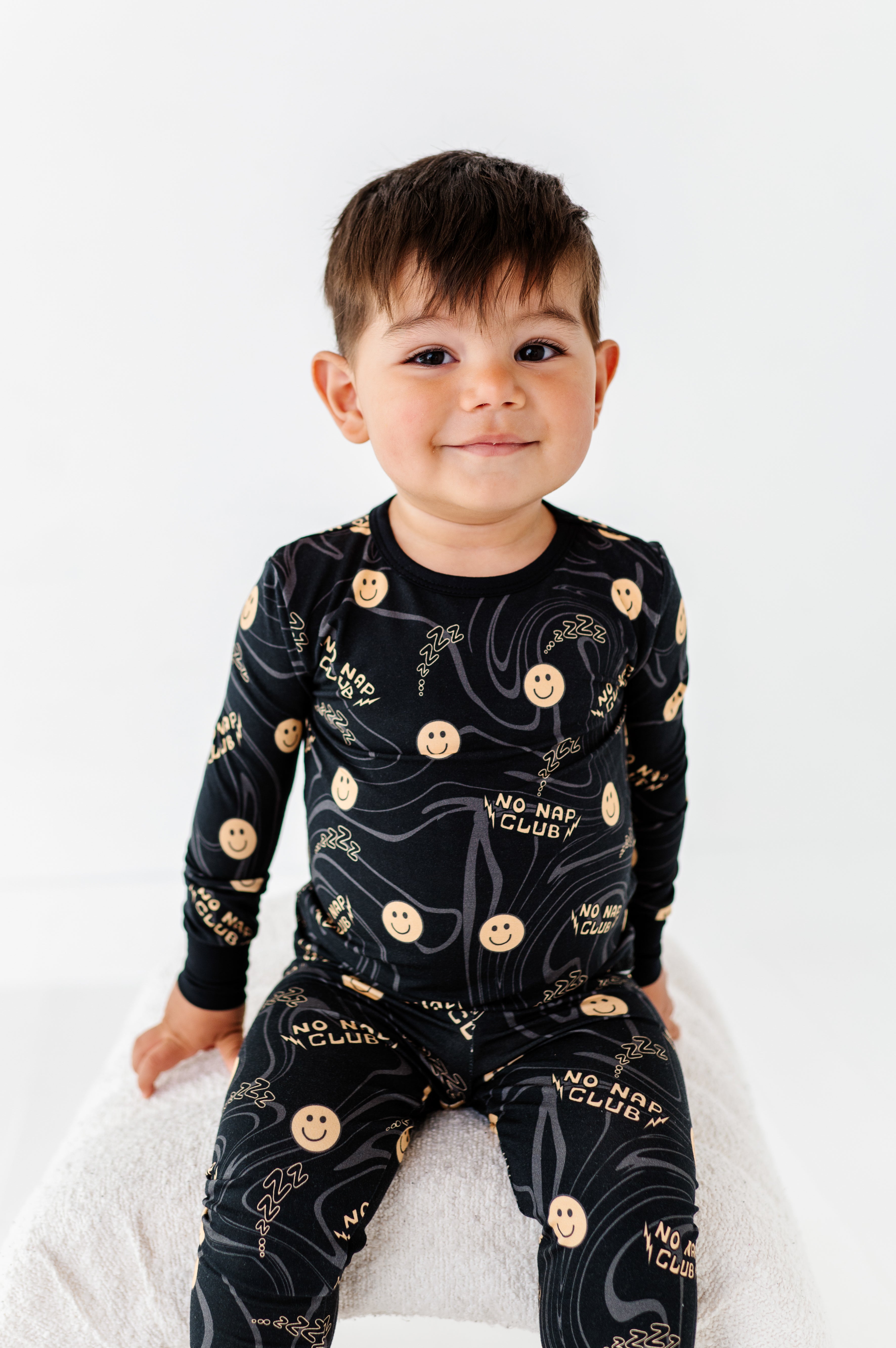 boy wearing Cute No Nap Club bamboo 2-piece set featuring smiley face graphics and a wavy pattern