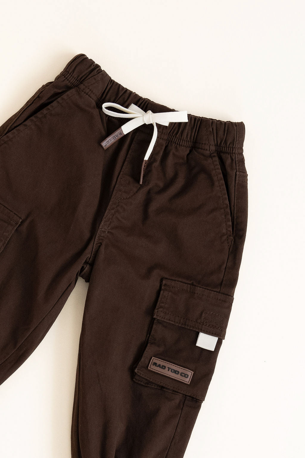 Brown cargo pants with a white drawstring on a white background