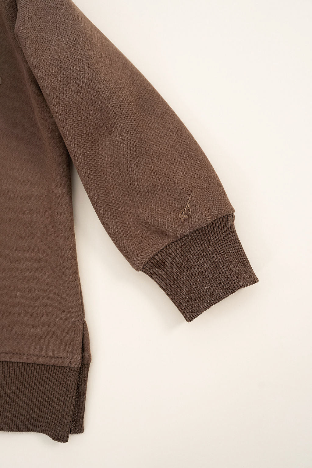 details  on Brown “Mama’s Boy” crewneck with slightly lighter brown lettering, laid flat on a neutral background.