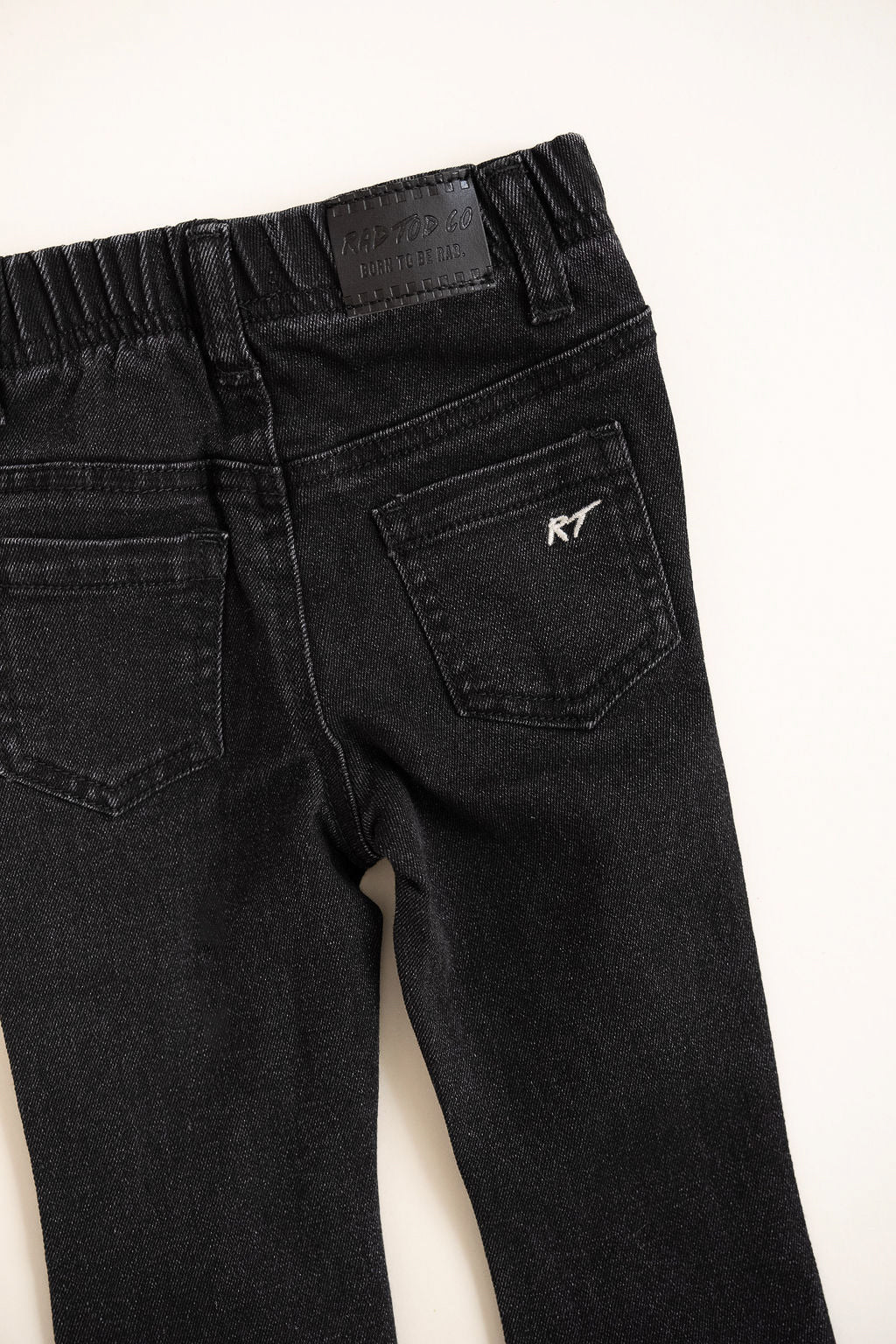 Black jeans with a brand logo on the back pocket against a white background