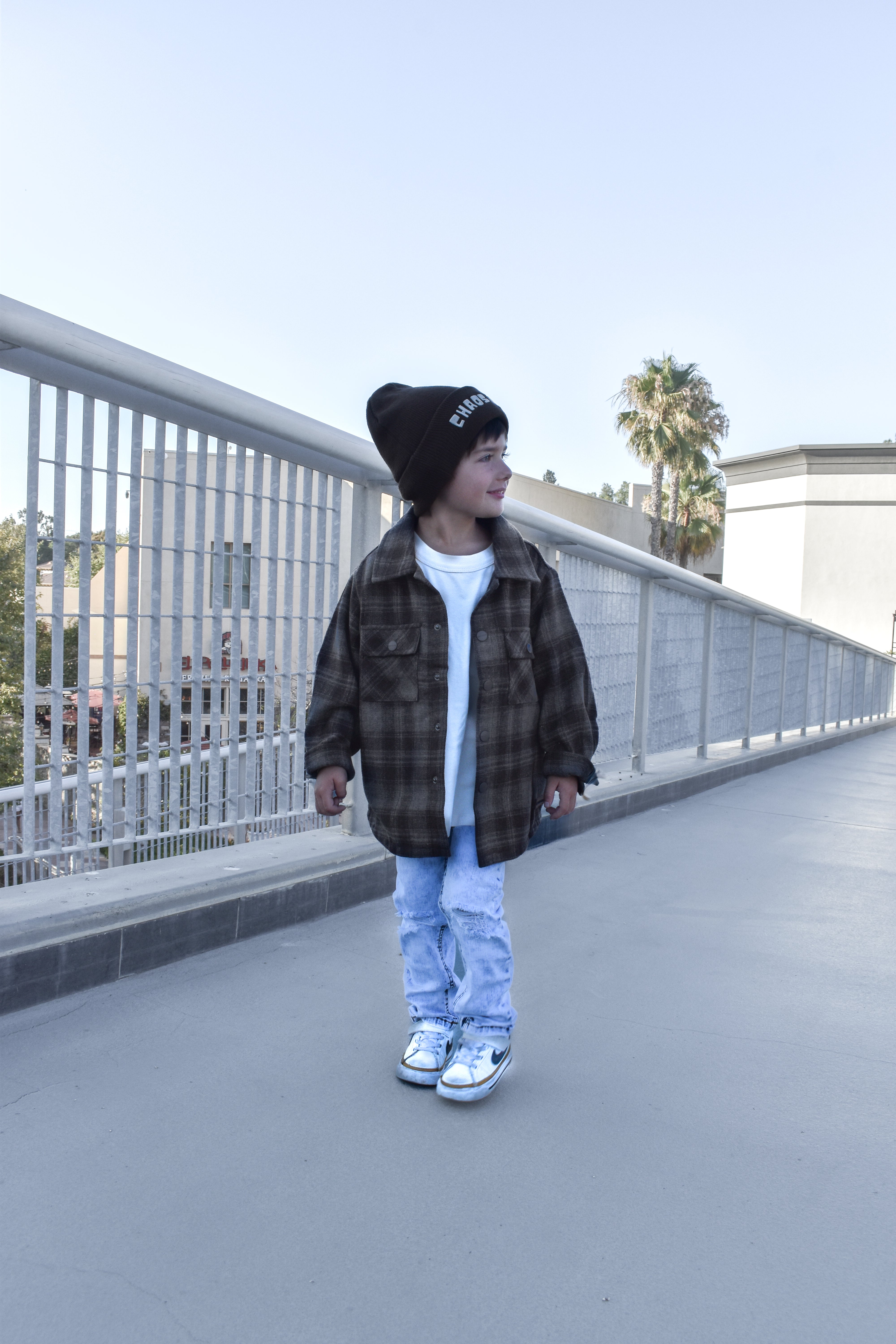 boy wearing espresso shacket standing by a fence