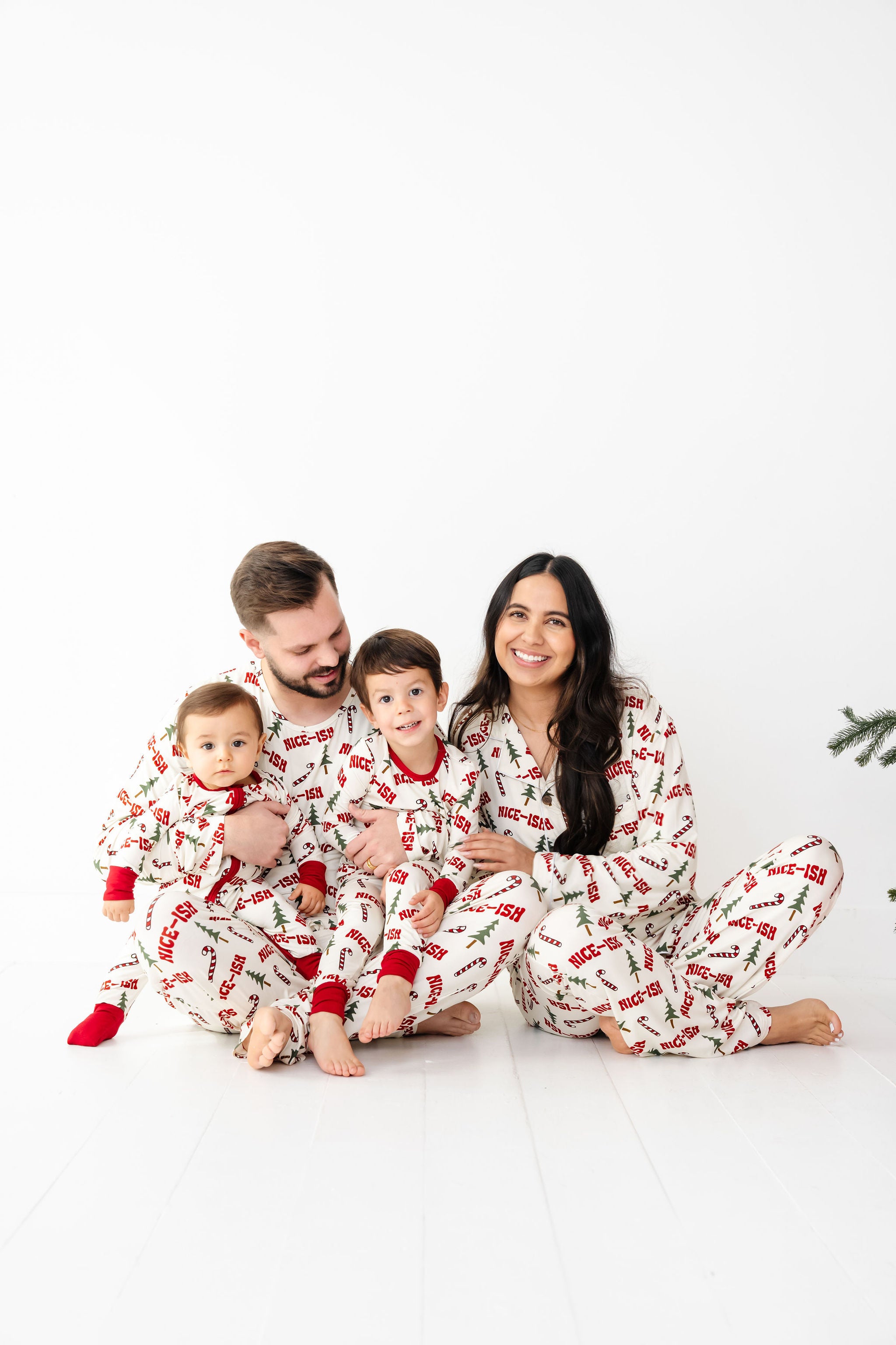 Family of four wearing matching pajamas on a white background