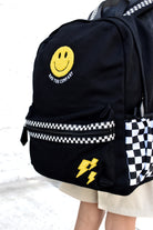 Black backpack with smiley face and lightning bolt design on a checkered background