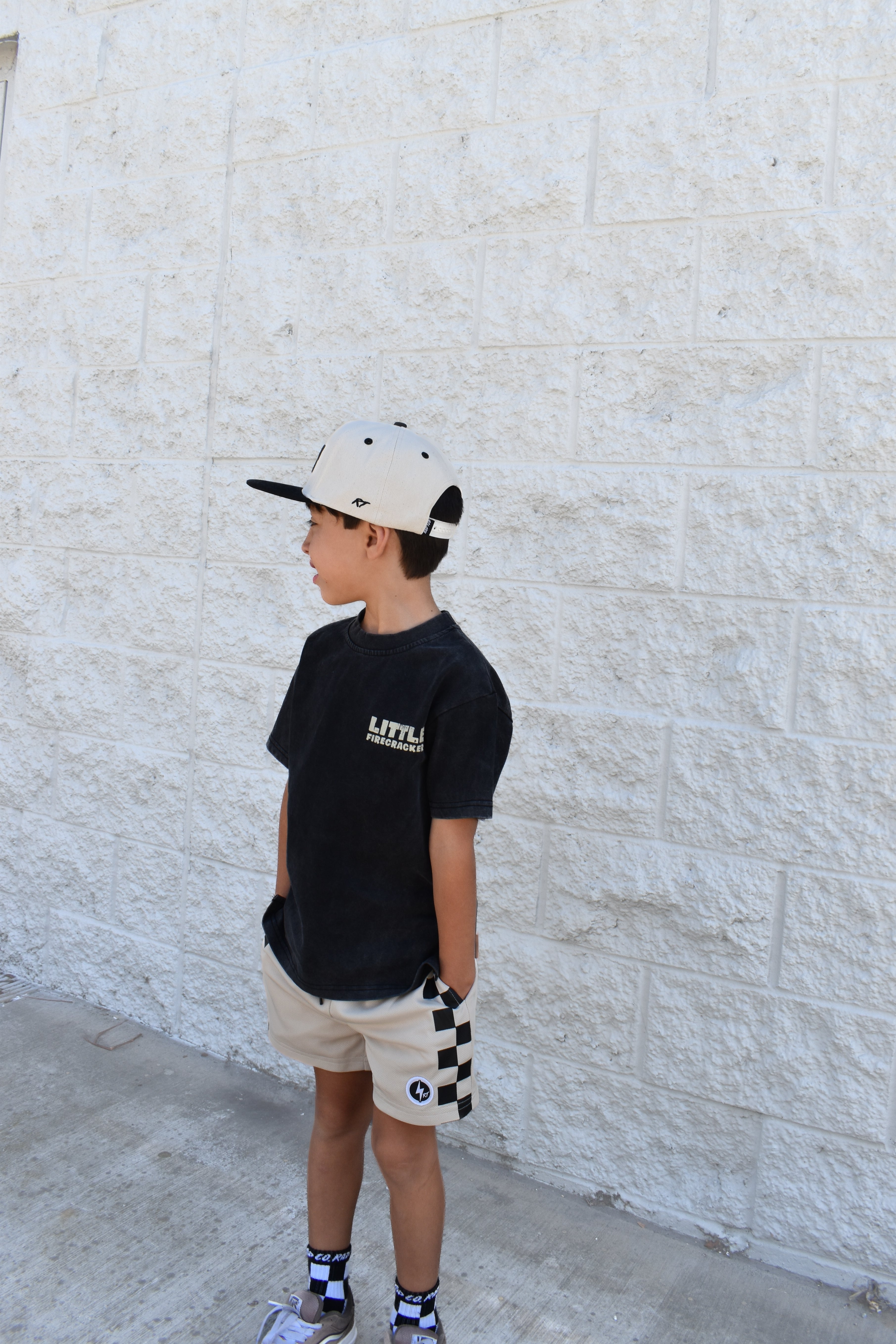 Kid wearing the Little Firecracker graphic tee on a black acid wash shirt with patriotic red, white, and blue design.