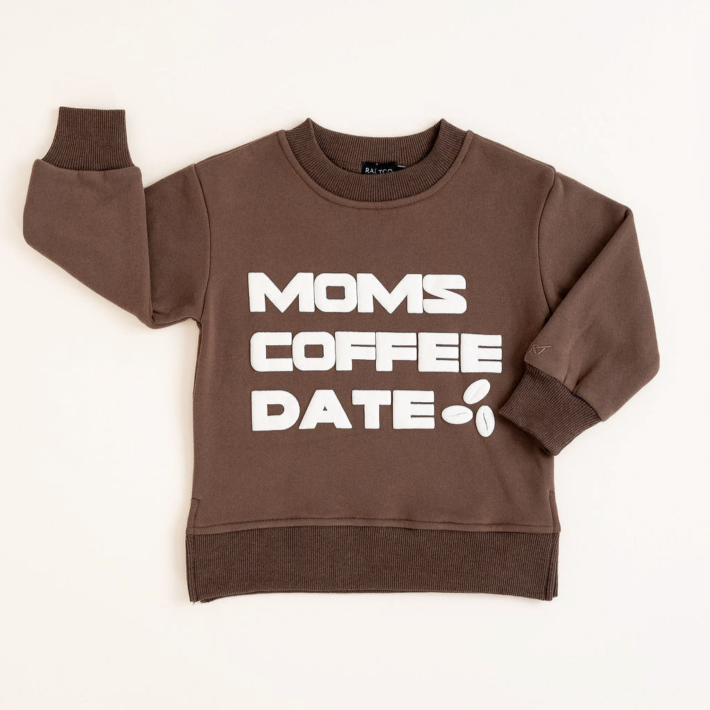 brown crewneck with bold off-white “Mom’s Coffee Date” lettering, laid flat on a neutral background.