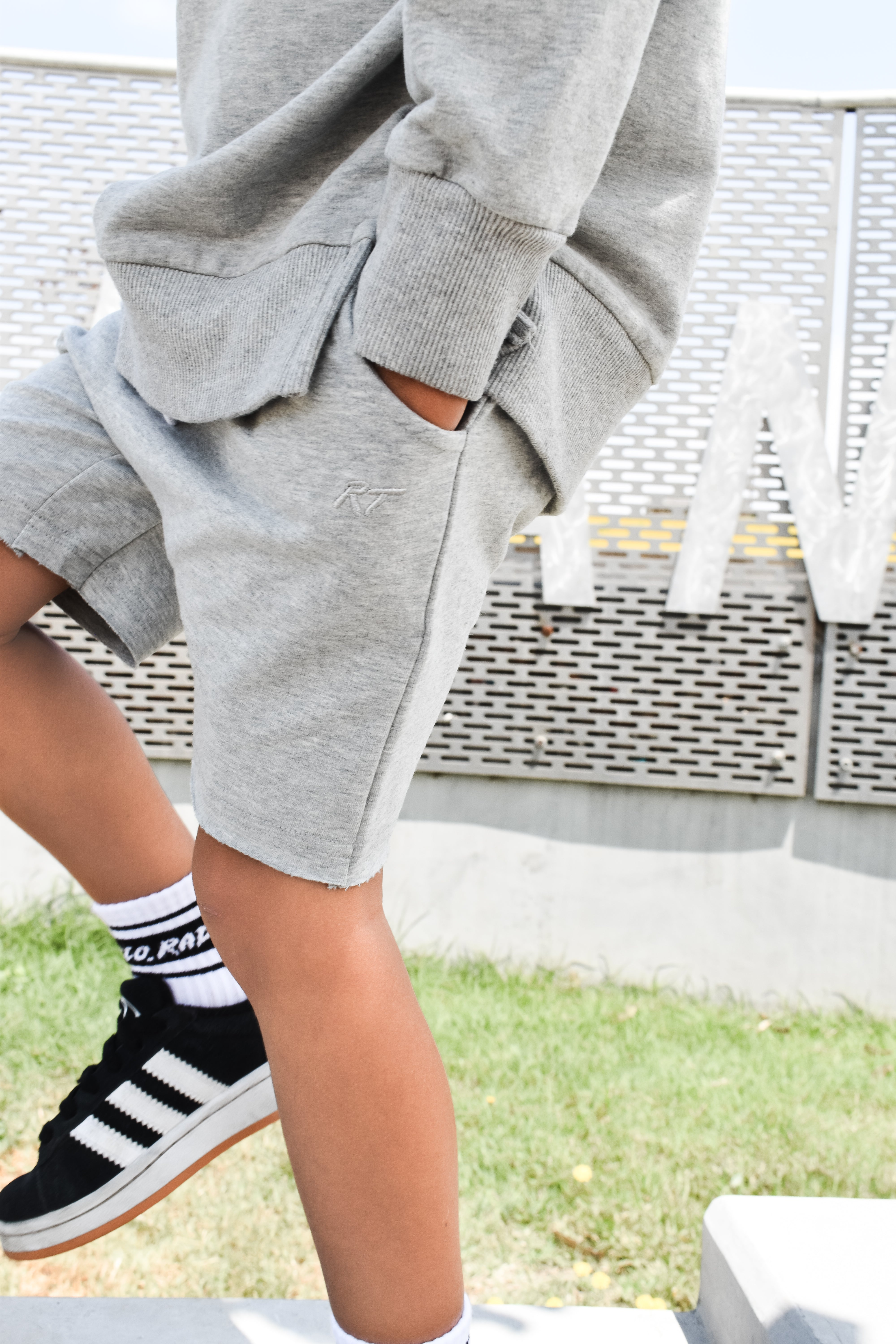 Young boy wearing gray Core Collection toddler shorts, standing outdoors and showcasing the relaxed, above-the-knee fit.