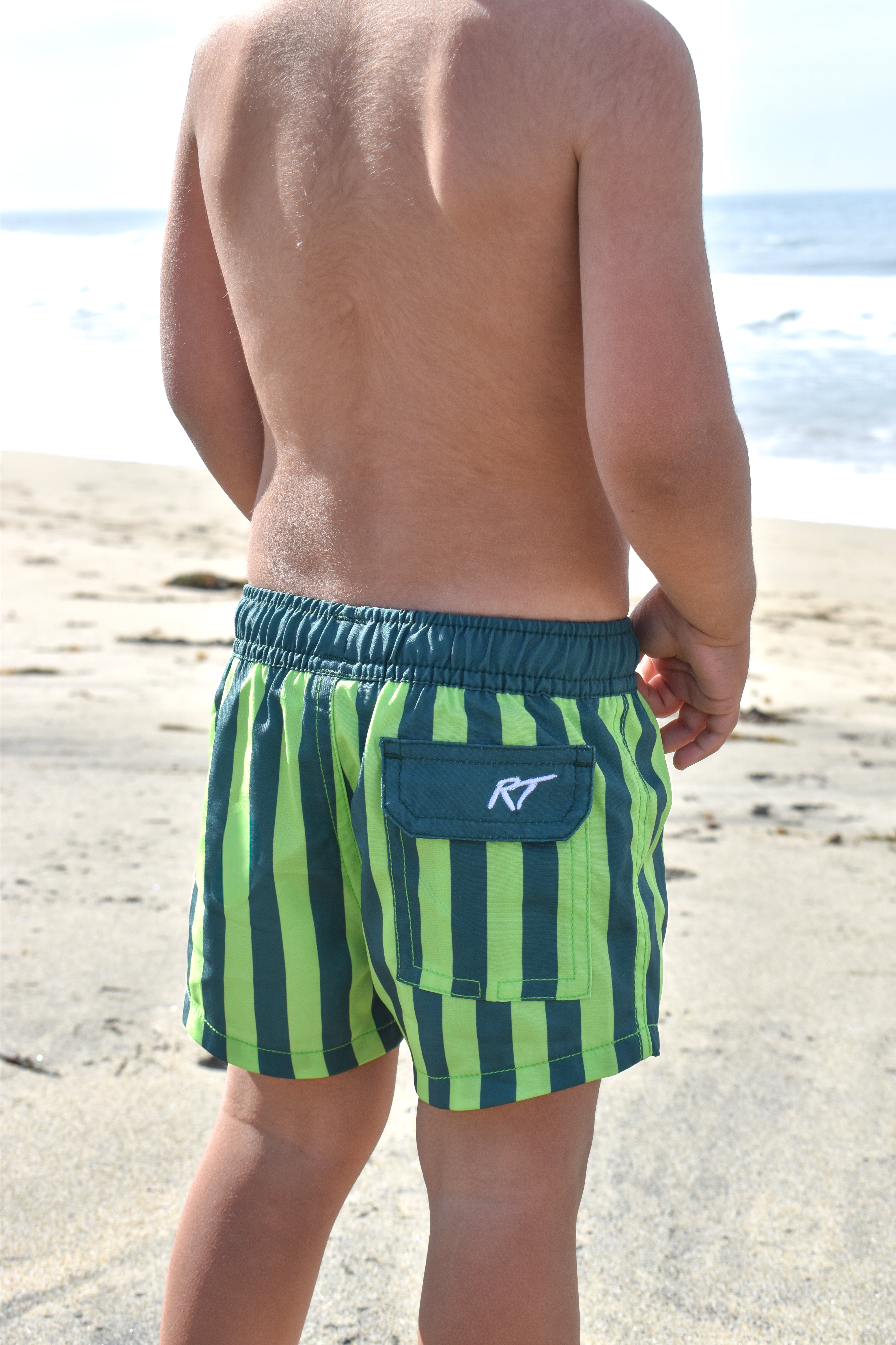 boy wearing green machine hi vis swimmie at the beach by Rad Toddler