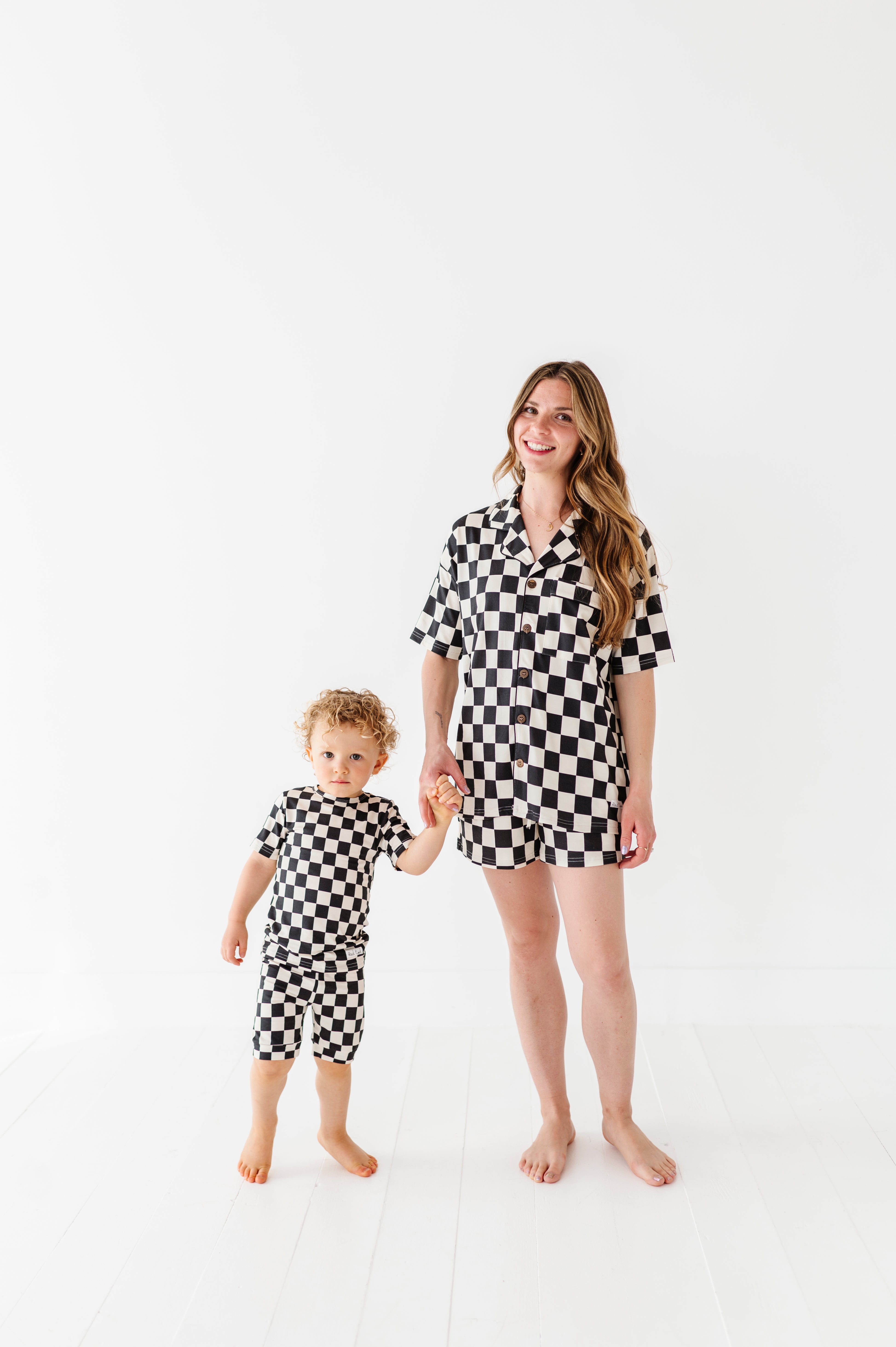hand in hand wearing Black and white checkered bamboo short sleeve pajama set for women, featuring soft, breathable fabric and a relaxed fit by Rad Toddler.