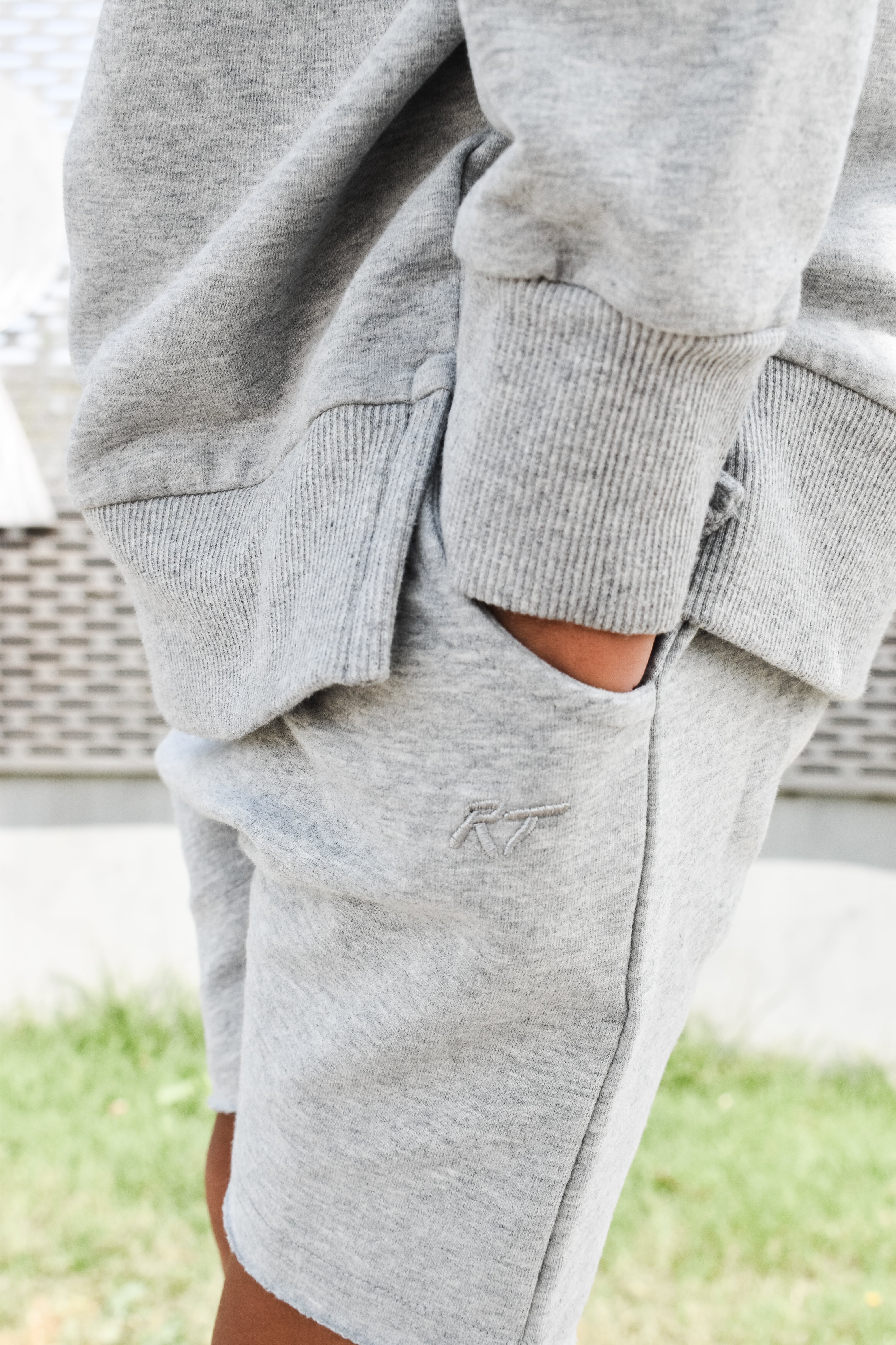 Young boy wearing gray Core Collection toddler shorts, standing outdoors and showcasing the relaxed, above-the-knee fit.