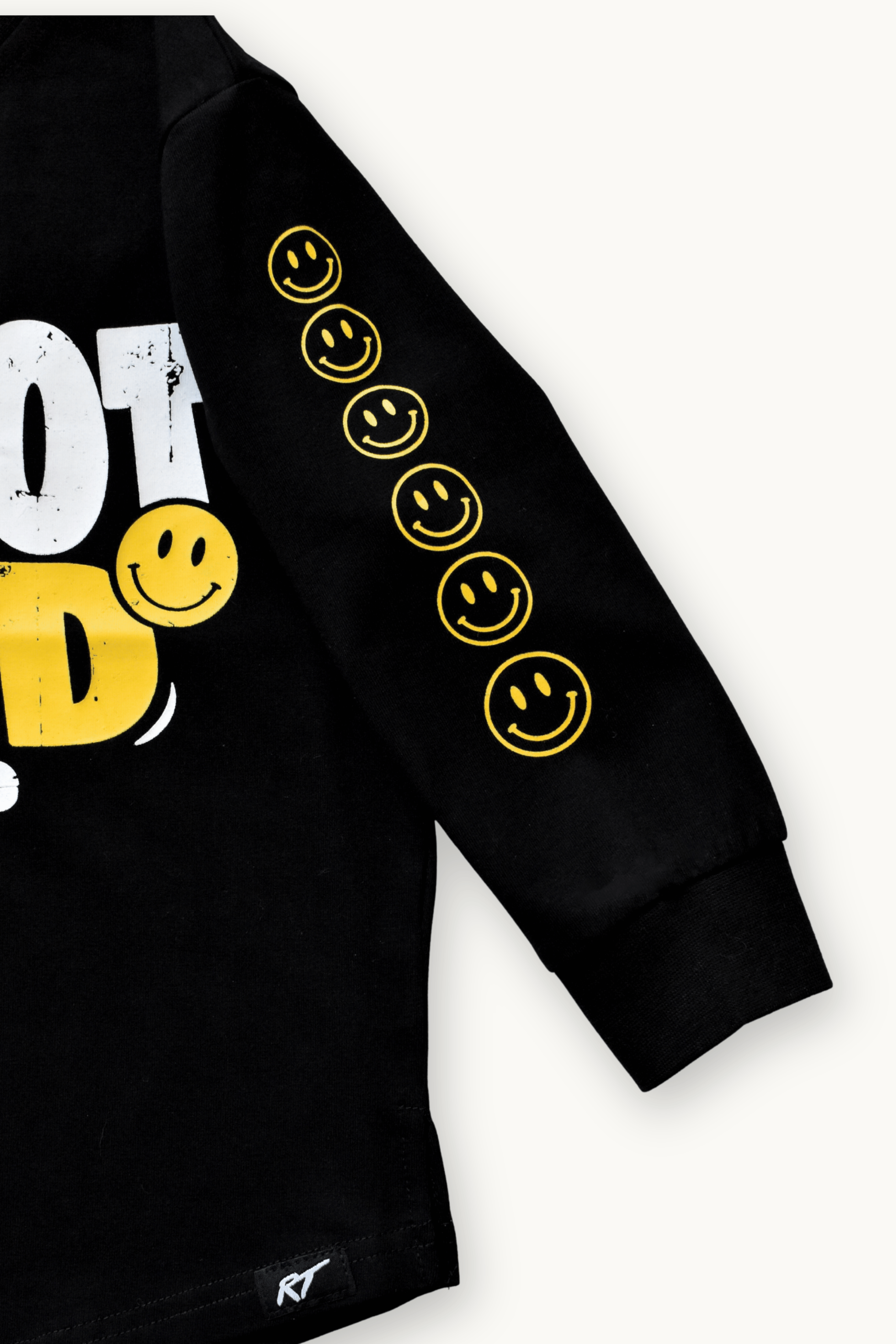 Close-up of a black long-sleeve sweatshirt with yellow smiley face graphics down one sleeve and a partial white and yellow graphic on the chest, shown on a light background.