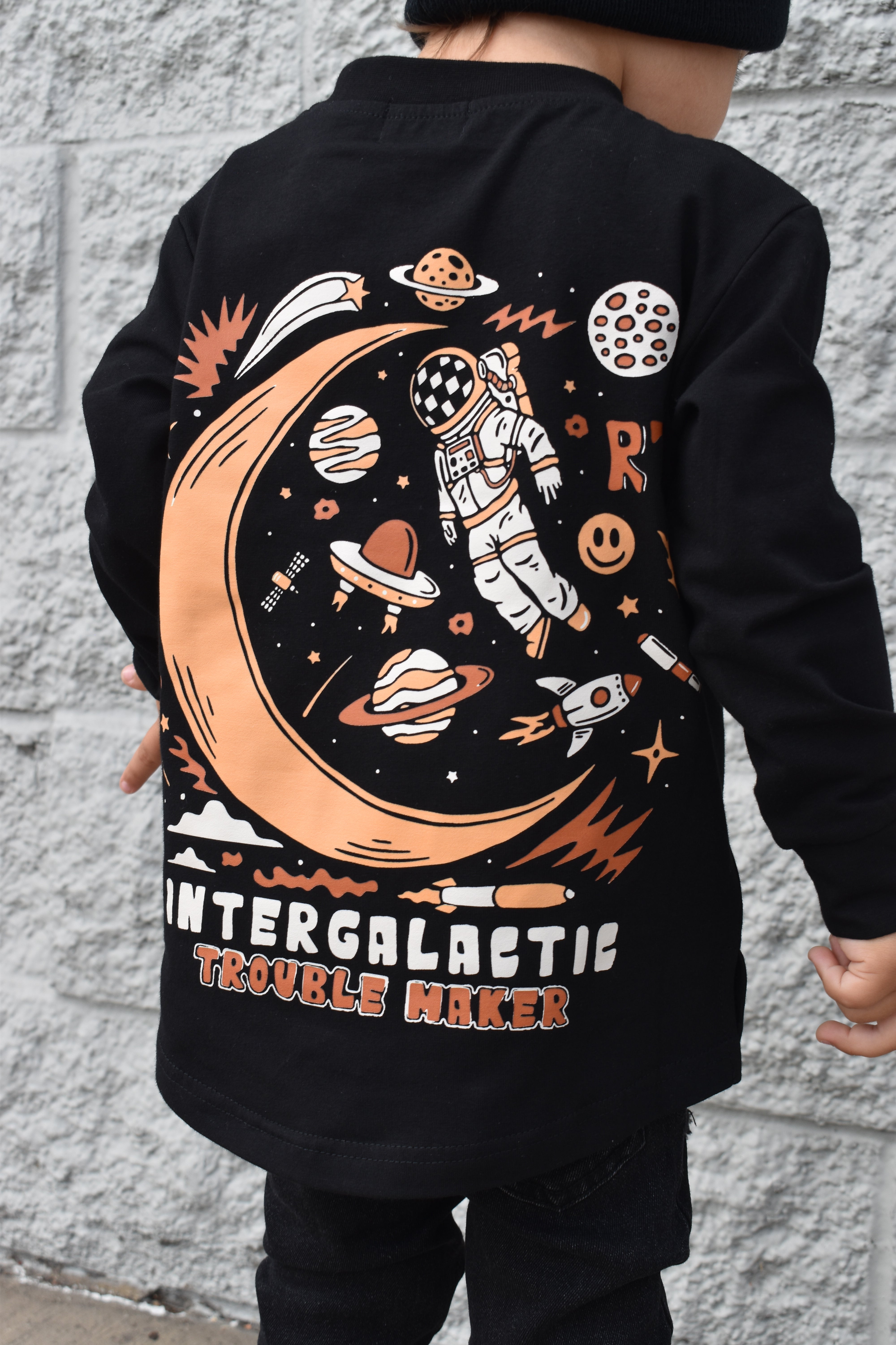 Lifestyle photo of boy wearing black Intergalactic Troublemaker long sleeve