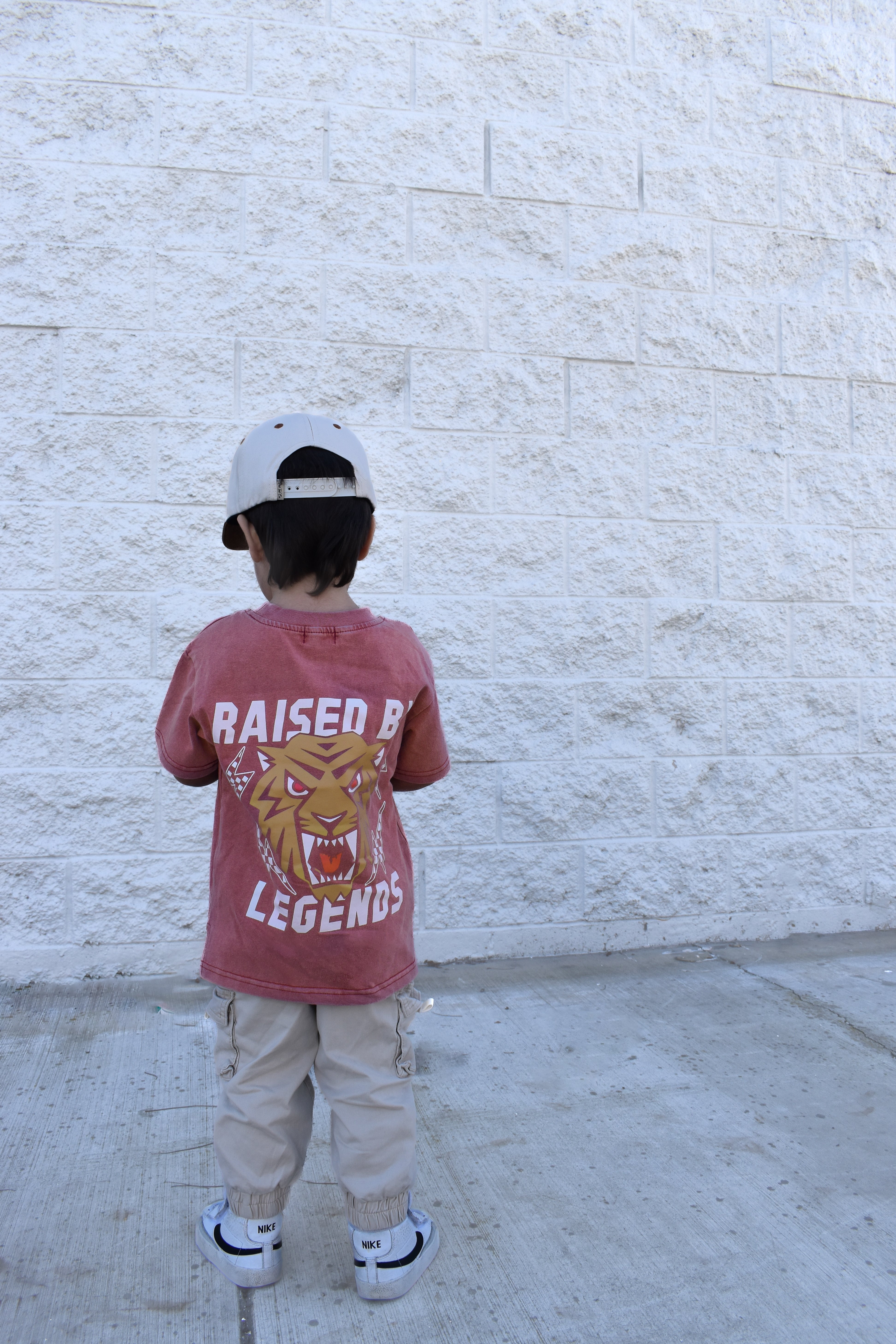 Cool kid wearing red acid wash Raised by Legends tiger t-shirt