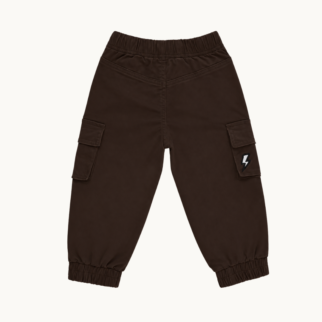 Dark brown cargo jogger pants with elastic waistband and cuffs, featuring side cargo pockets and a small white lightning bolt logo patch on the right pocket, shown flat on a light cream background.