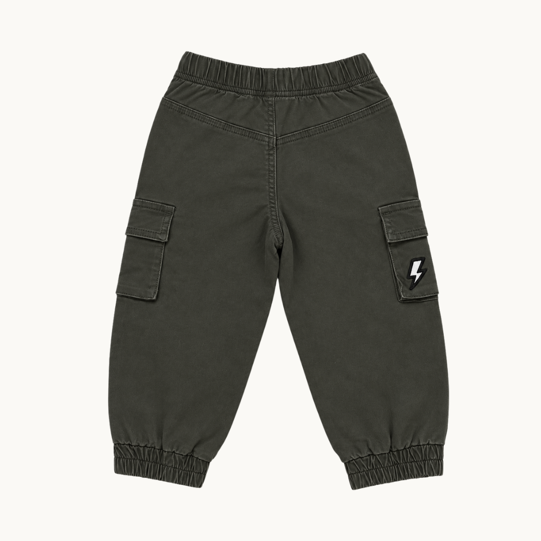 A pair of dark olive green cargo jogger pants with elastic waistband and ankle cuffs, featuring a small white lightning bolt patch on the right pocket, shown flat on a light off-white background.