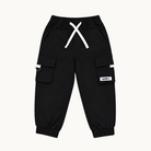 Black cargo jogger pants with white drawstrings, side cargo pockets, and a small white brand patch on the left leg, shown flat on a light cream background.
