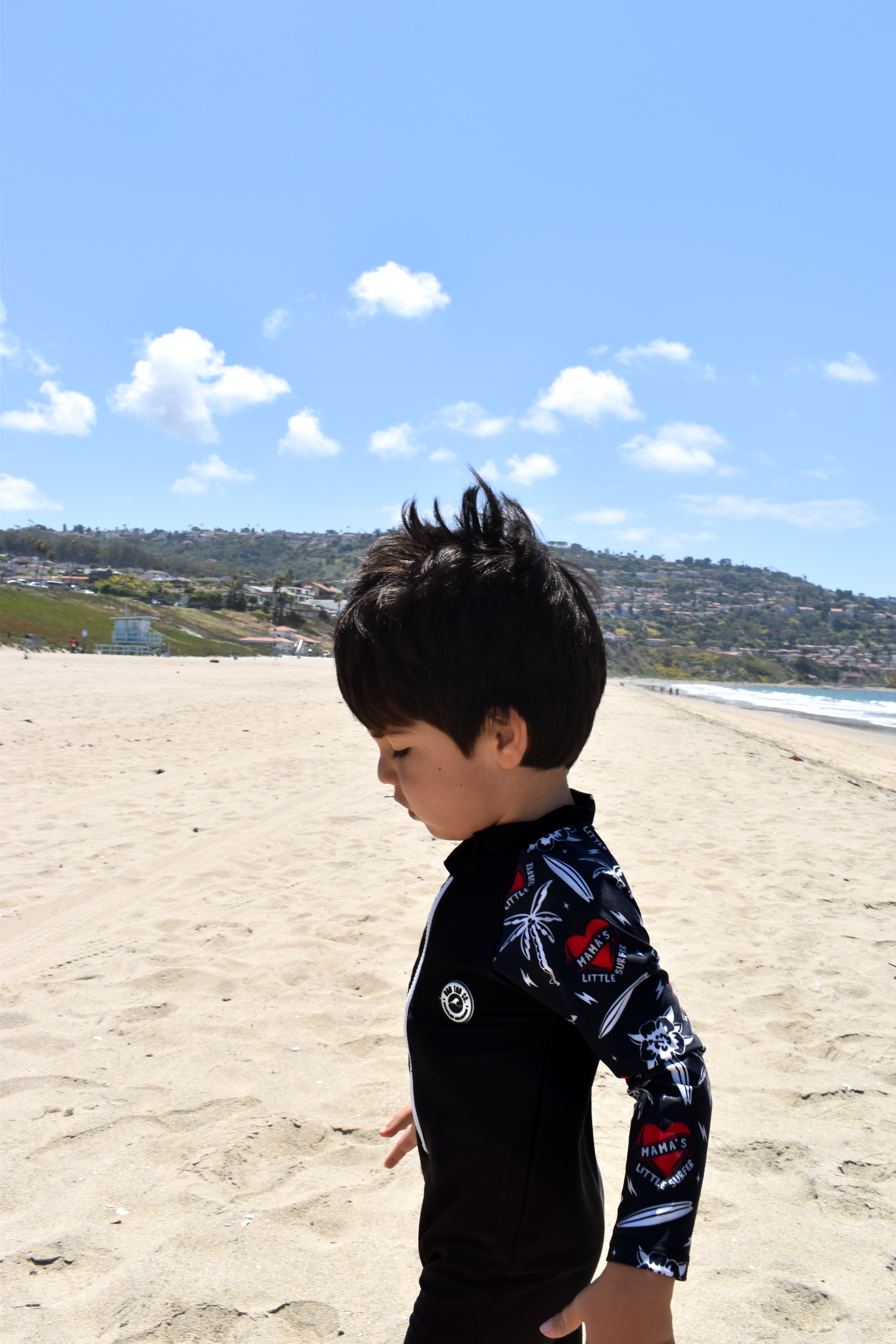 Child wearing rashguard onesie at the beach by rad toddler
