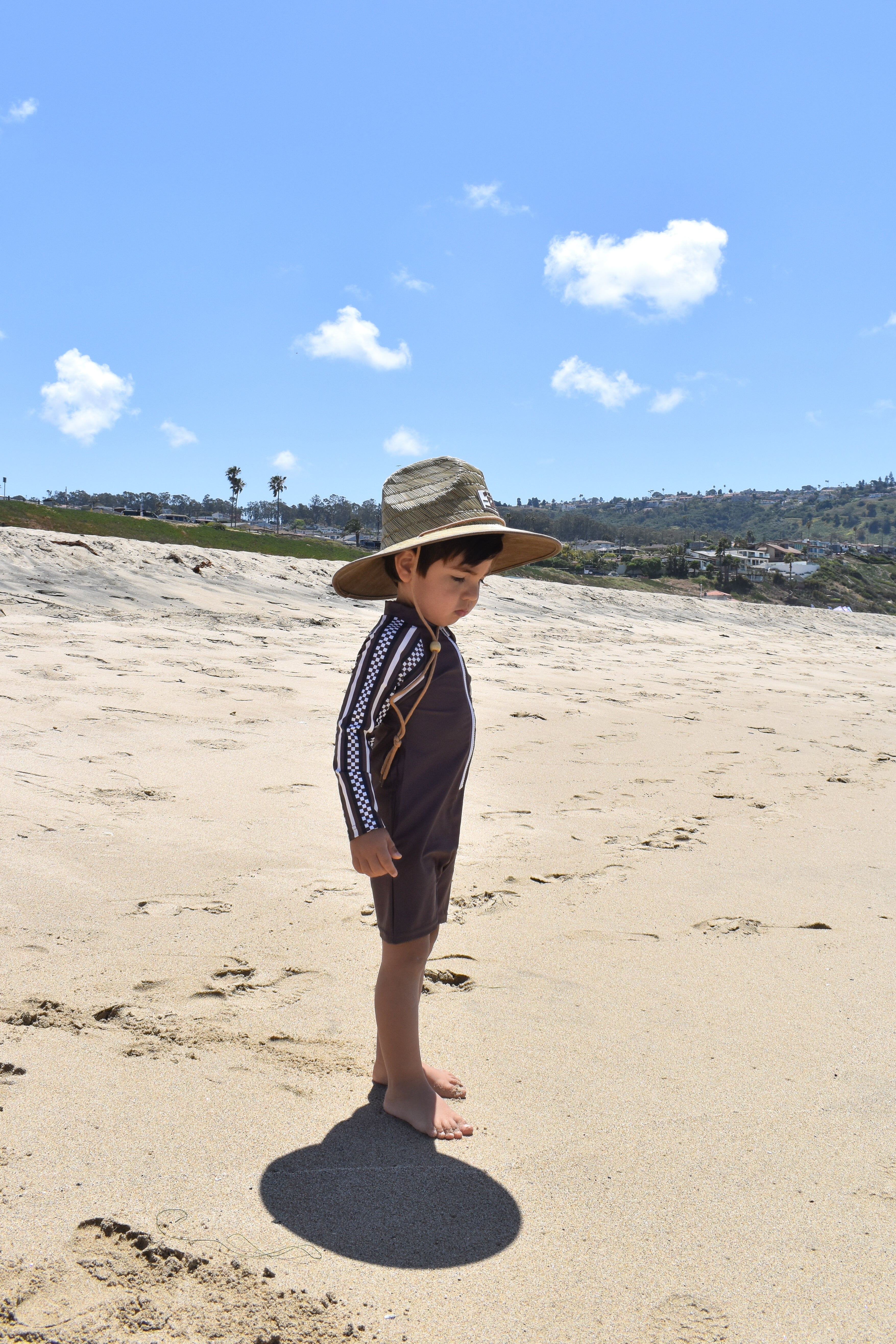 Child wearing mocha rashguard onesie at beach by rad toddler