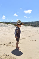 Child wearing mocha rashguard onesie at beach by rad toddler