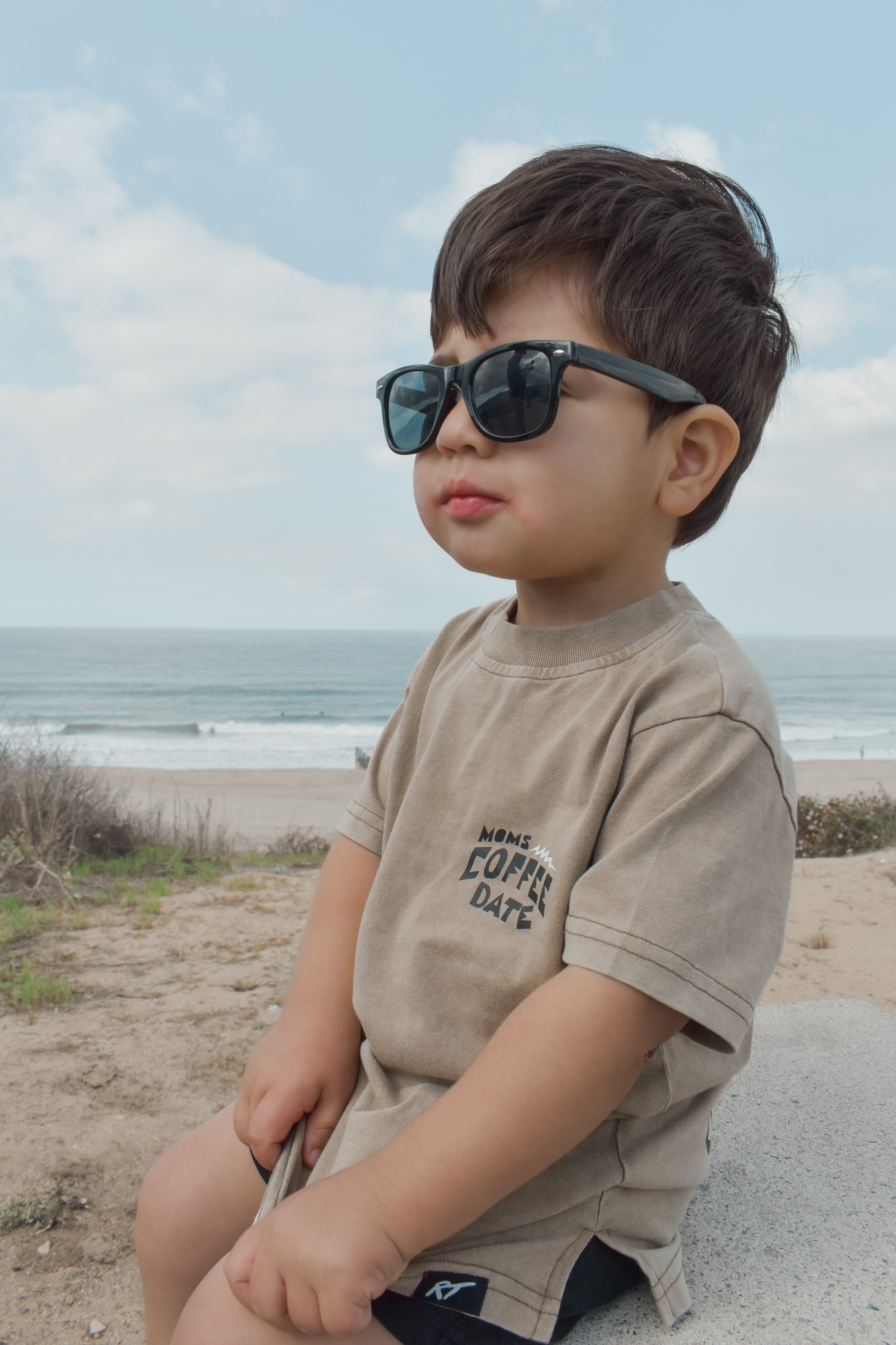 boy wearing moms coffee date t shirt stares onward probably looking at mom