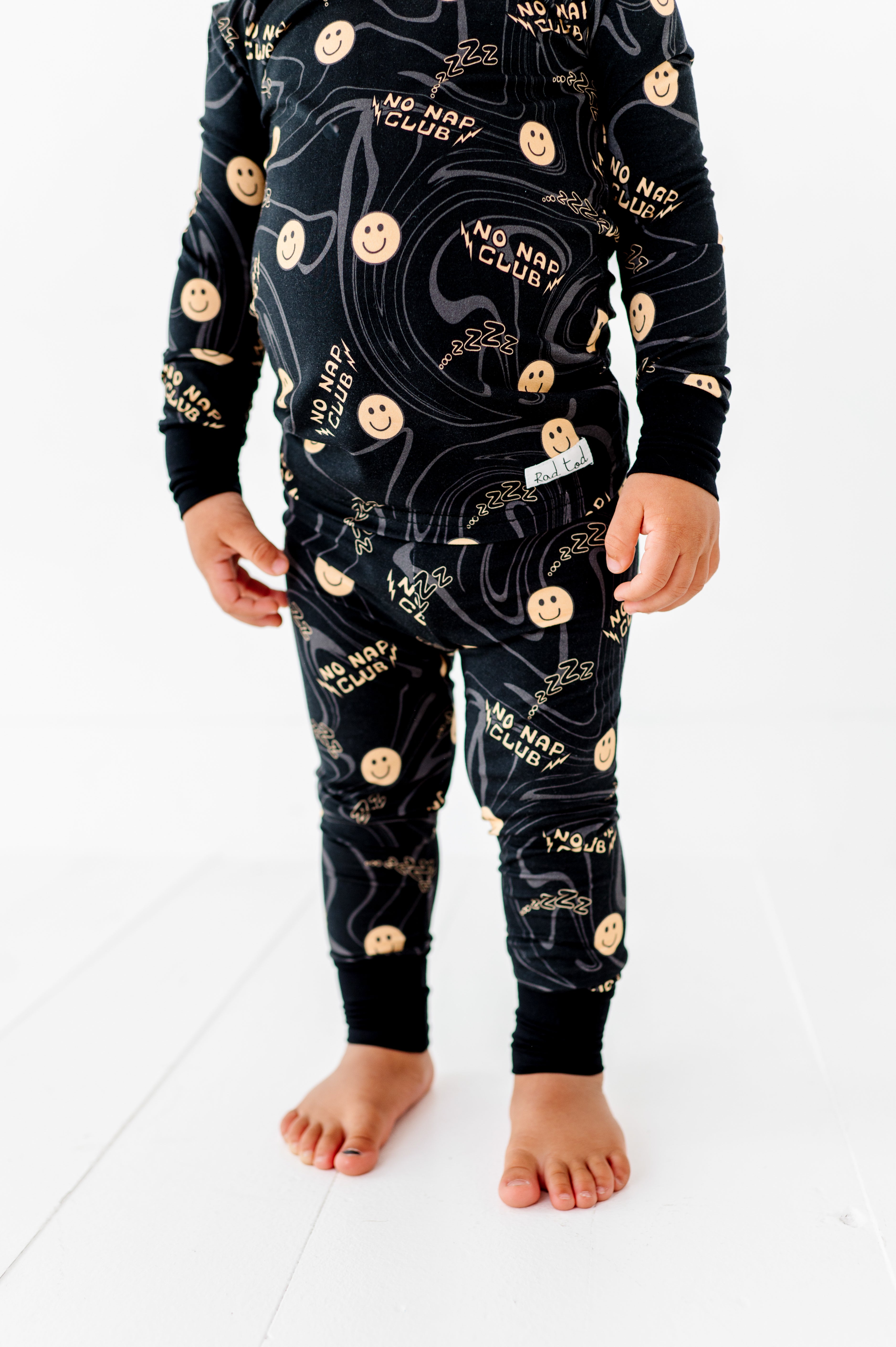 boy wearing No Nap Club bamboo 2-piece set for toddlers with smiley faces and wavy line pattern
