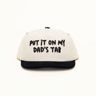 Front view of Put It On My Dad’s Tab kids snapback with playful embroidery on off-white crown and black bill.