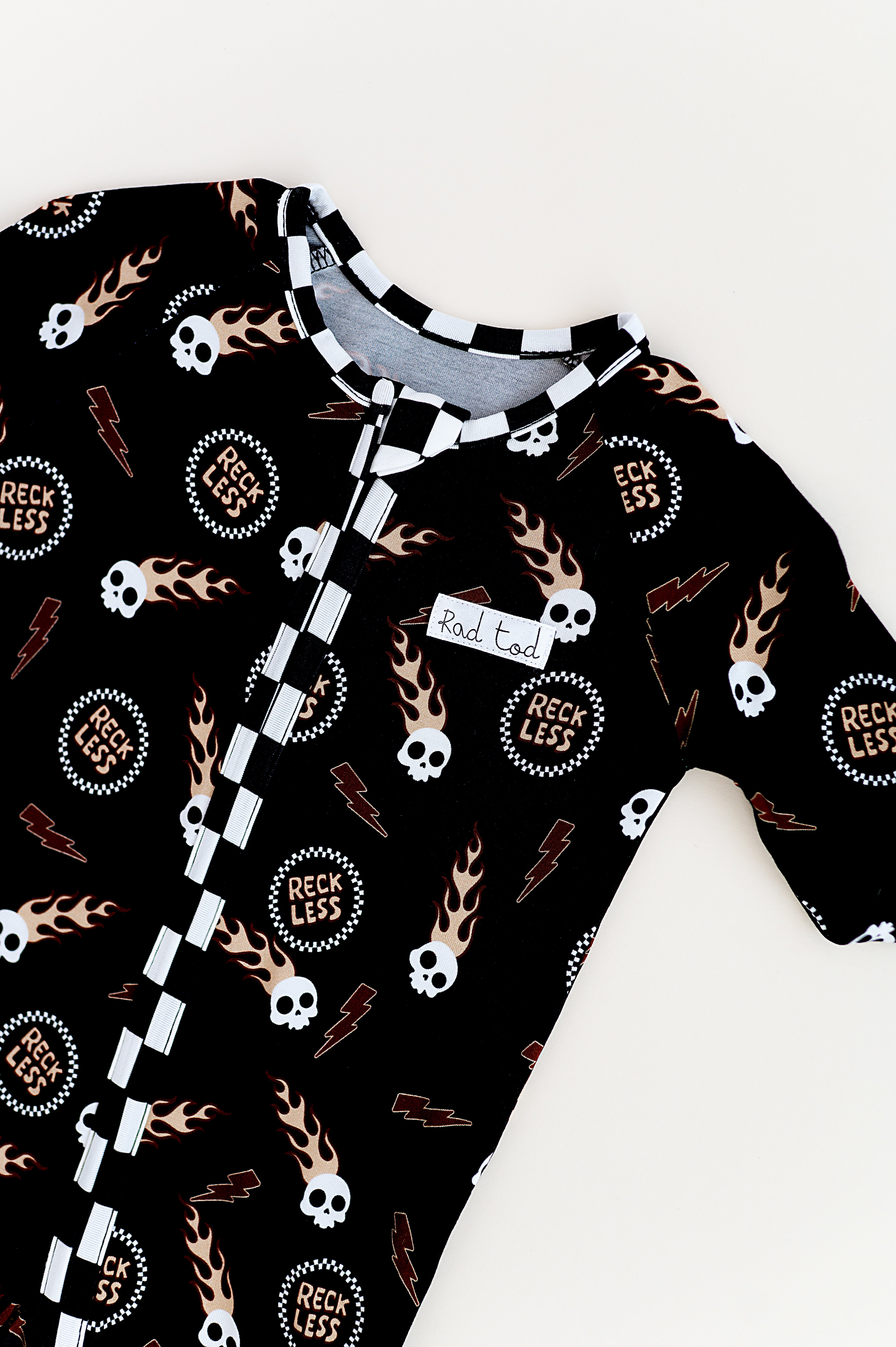 Edgy toddler onesie with checker print, flaming skull, and soft bamboo fabric