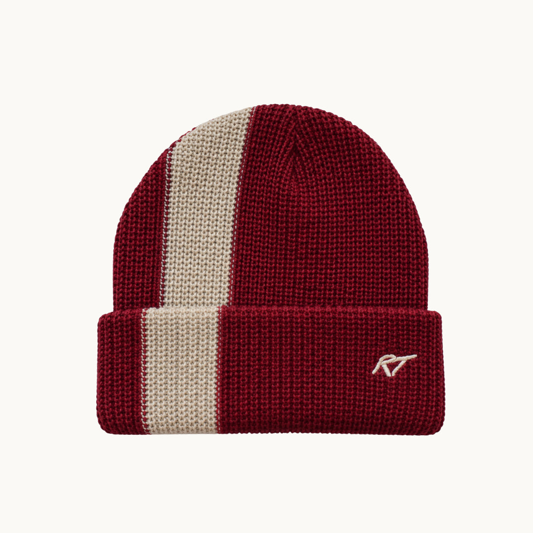 A ribbed knit beanie hat in burgundy and cream, featuring a vertical cream stripe on the side and a small embroidered logo on the cuff, shown against a plain off-white background.