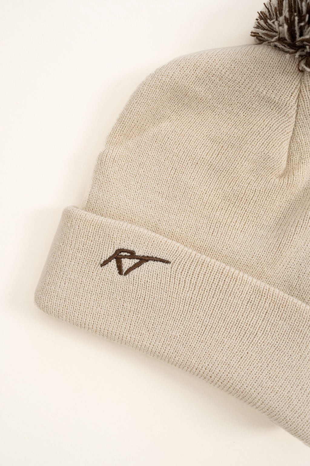 Beige beanie with a logo on a light beige background