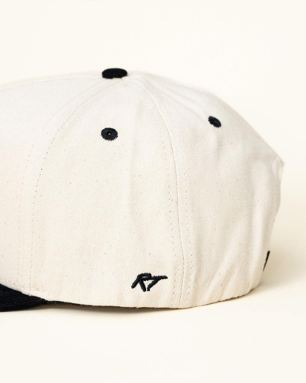 Side view of kids snapback showing the playful embroidered text on off-white and black hat.