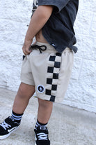 boy wearing Sand check shorts with relaxed fit, lightweight polyester fabric, and everyday streetwear style