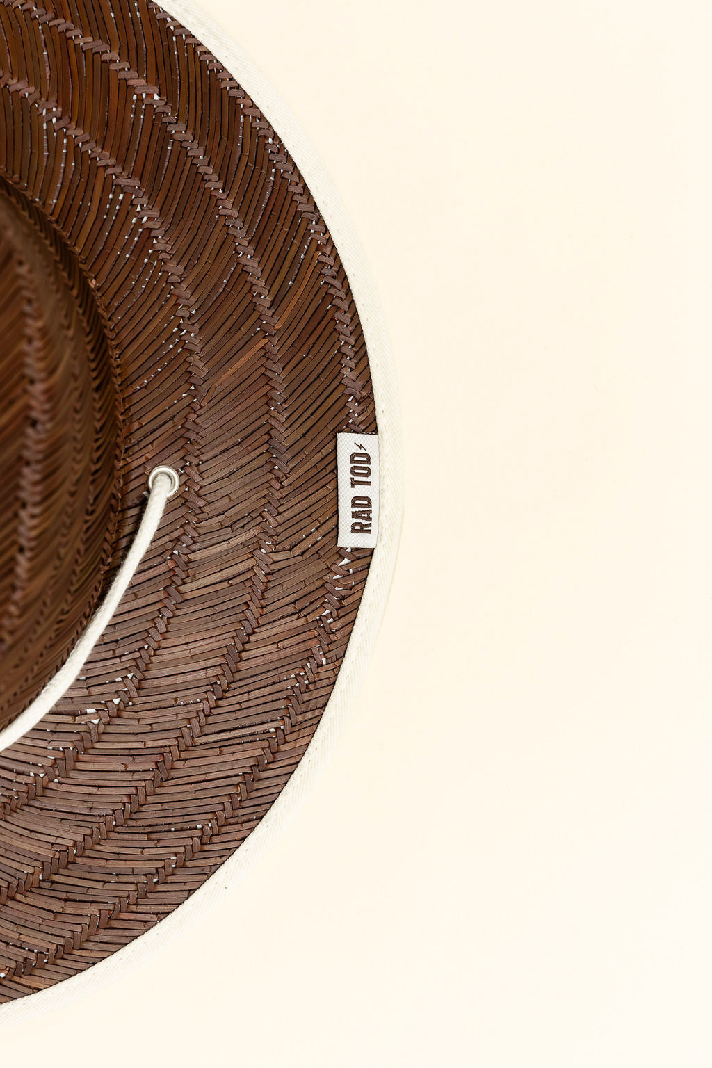 details on Sandbar straw hat with dark straw exterior and beige detail under the brim, wide brim providing sun protection for face, ears, and neck by Rad Toddler
