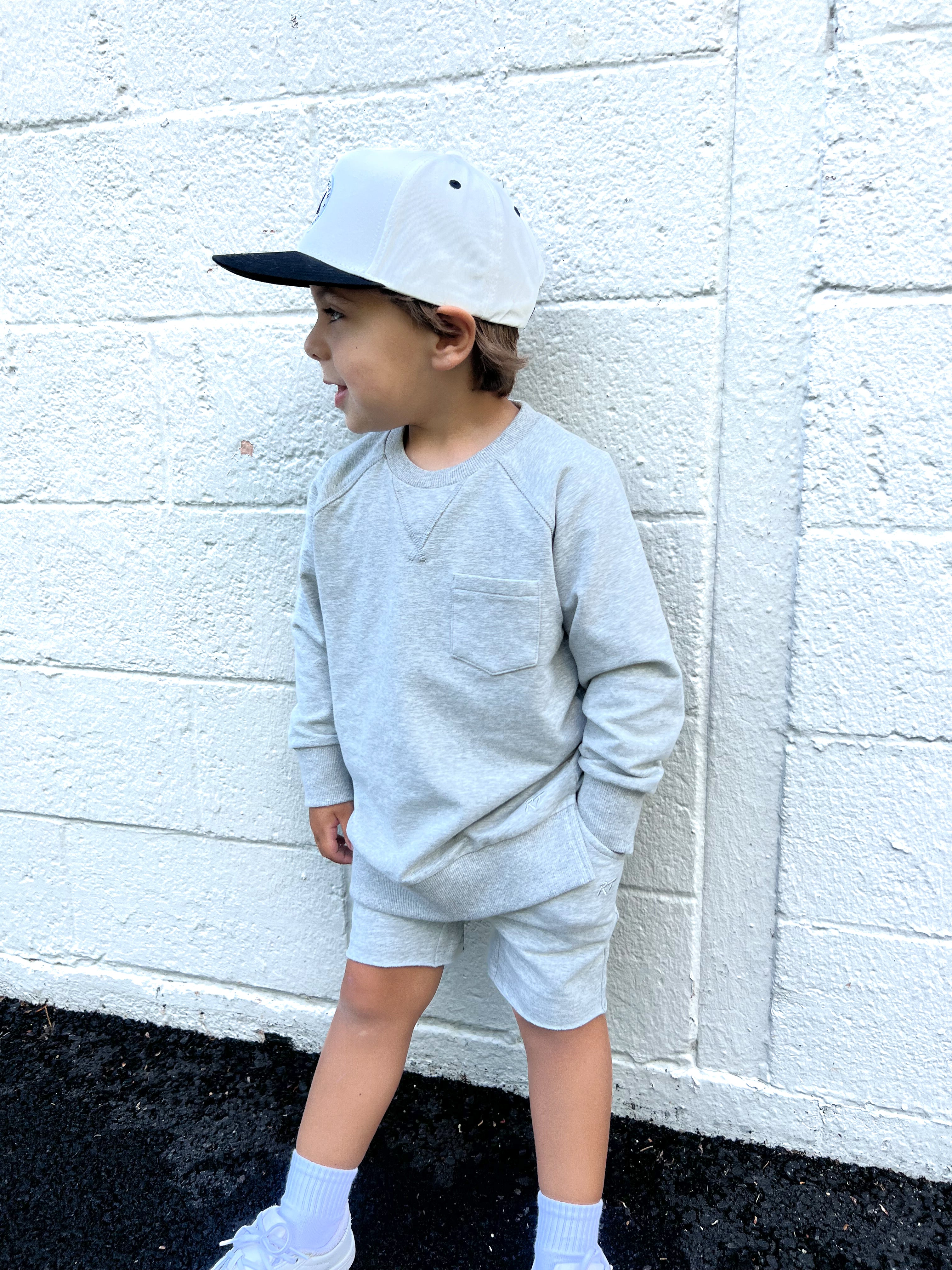 Young boy wearing gray Core Collection toddler shorts, standing outdoors and showcasing the relaxed, above-the-knee fit.