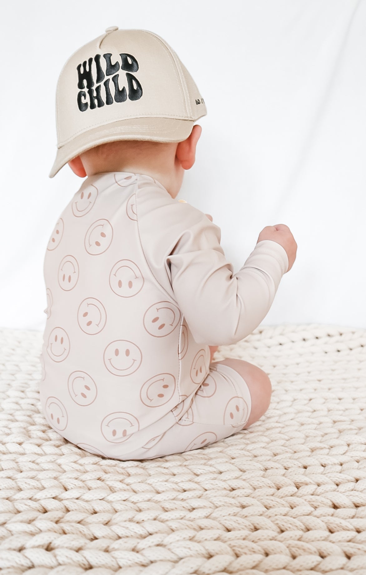 boy wearing Rad Toddlers Smiley Shore One-Piece Rashguard in beige with smiley face design, featuring easy zipper and UPF 50+ sun protection.