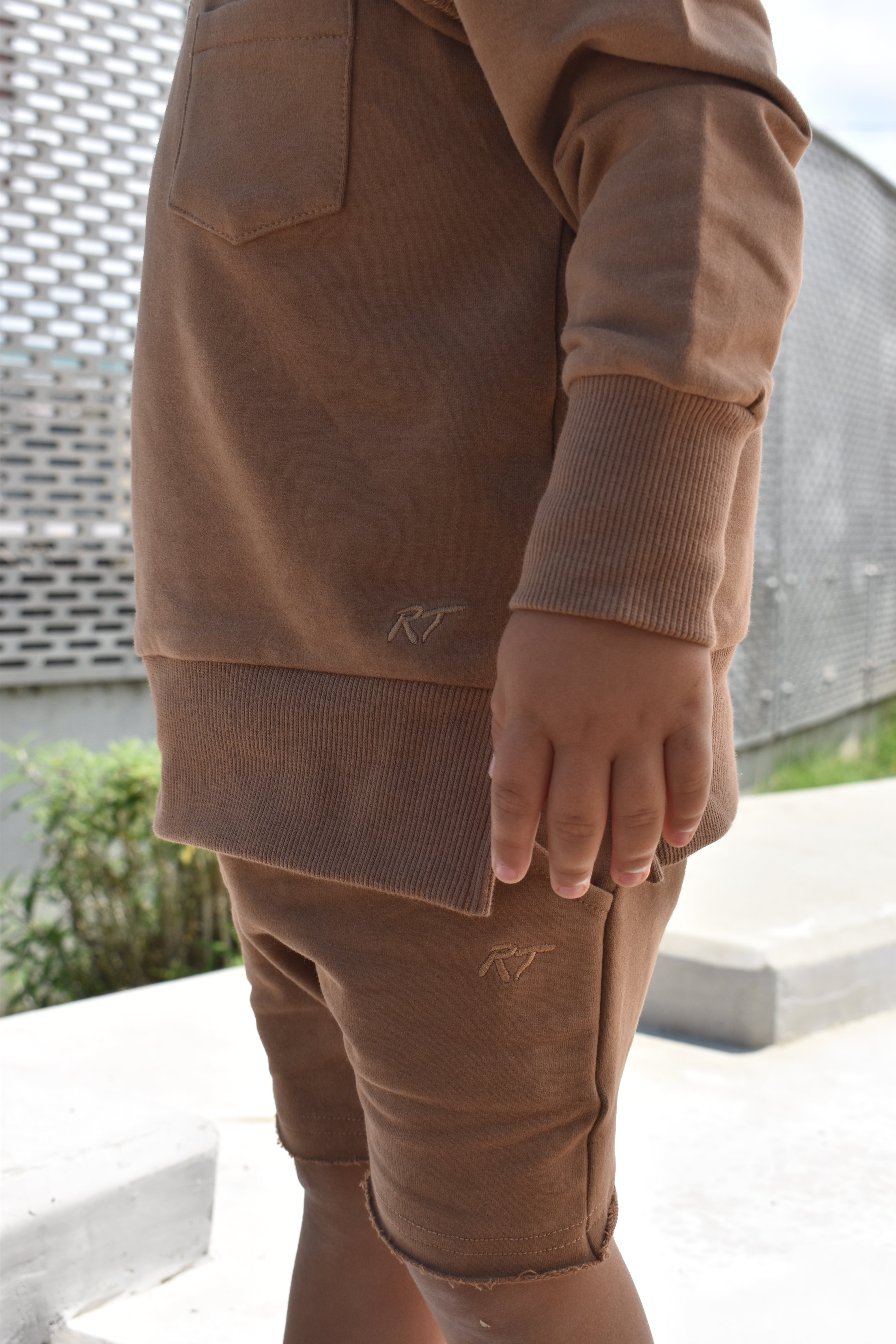 Young boy wearing almond Core Collection toddler crewneck with oversized fit, standing outdoors.