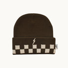 A dark brown knit beanie with a folded cuff featuring a cream and brown checkerboard pattern and a small cream lightning bolt logo, shown on a light off-white background.
