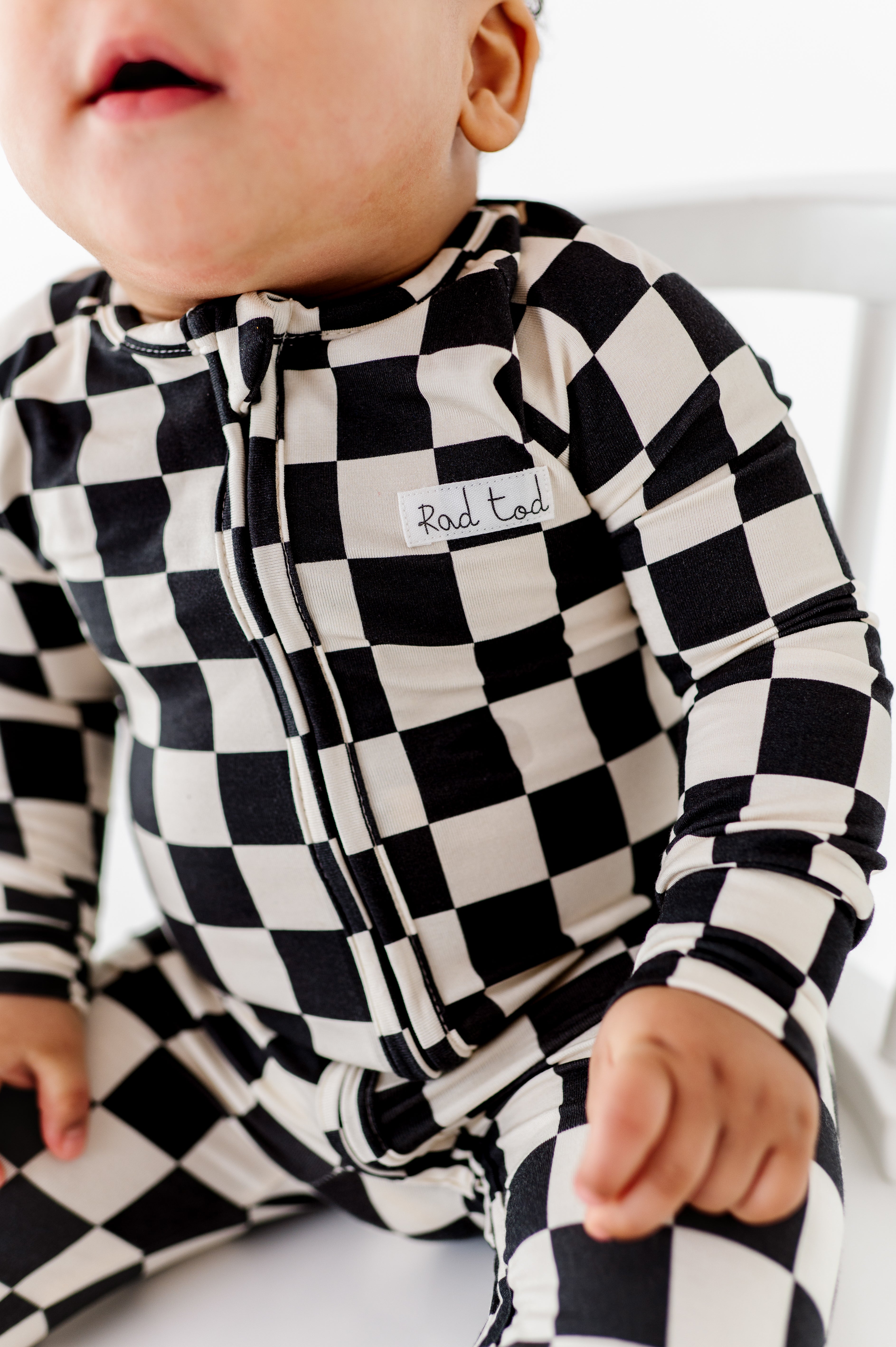 Close-up of two-way YKK zipper on checkered bamboo baby onesie