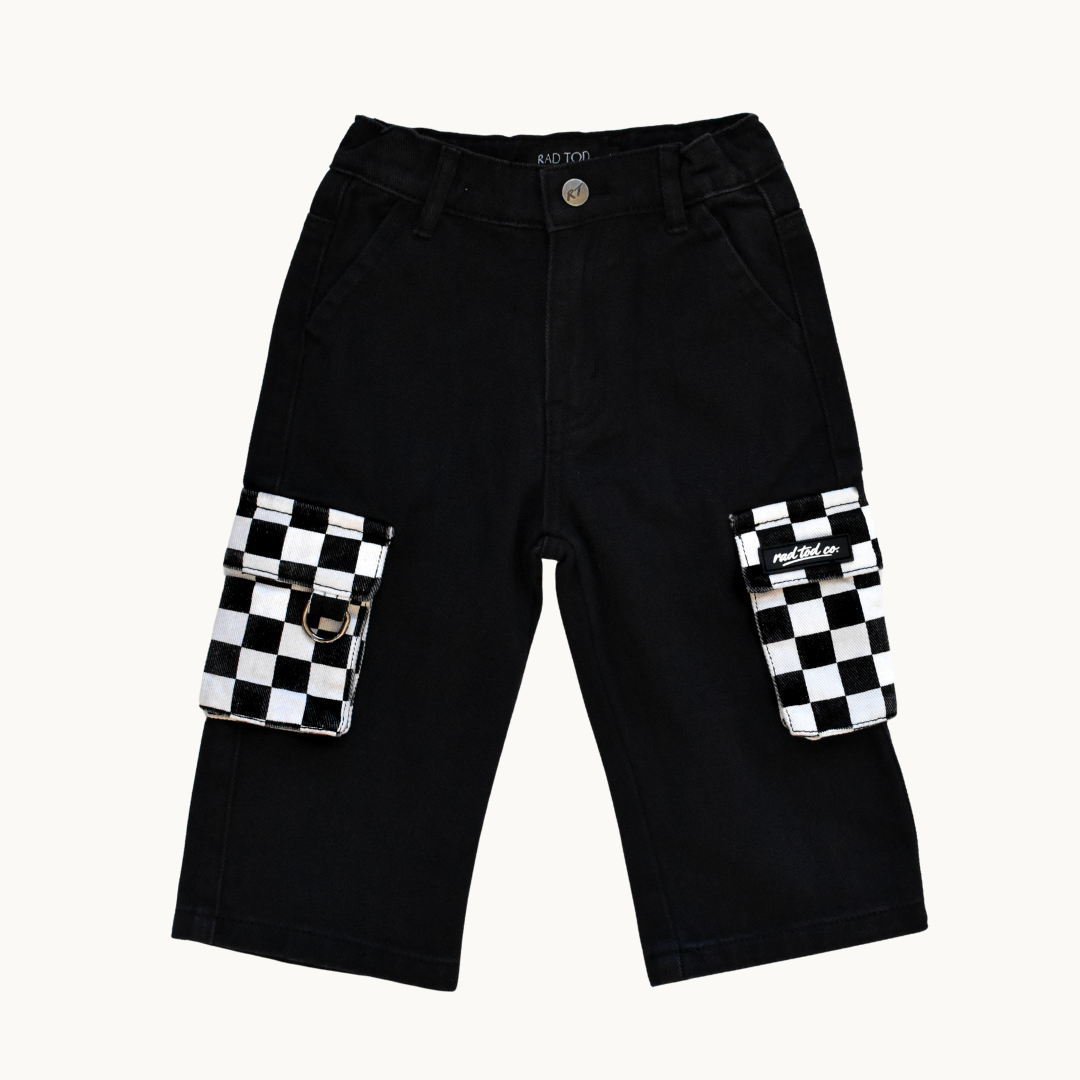 Black cargo shorts with large flap pockets featuring a black and white checkered pattern, shown flat on a light cream background.